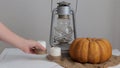 Woman puts a candle on a table next to a pumpkin and lantern