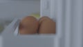 Woman puts chicken eggs into plastic compartment of fridge