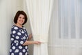 Woman puts clamps on curtains in apartment Royalty Free Stock Photo