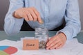 Woman puts coin into jar labelled Home. Royalty Free Stock Photo