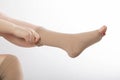 A woman puts on compression stockings for legs with varicose veins. Pain and swelling in the legs, phlebology. White