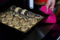 A woman puts curlicues stuffed with poppy and walnuts in the oven. For baking