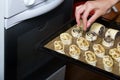 A woman puts curlicues stuffed with poppy and walnuts in the oven. For baking