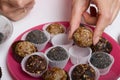 Woman puts dried fruit candies on a plate. Balls of prunes, dates and coconut. With a sprinkle of black sesame powder Royalty Free Stock Photo