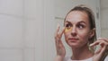 Woman puts golden collagen pads under her eyes and looks at the mirror Royalty Free Stock Photo