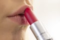 A woman puts red lipstick on her lips in front of a mirror , selective focus, close-up. Royalty Free Stock Photo