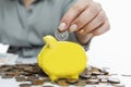 A woman puts a Russian coin into a yellow piggy bank. Investing and savings. Close-up