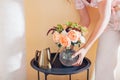 Woman puts vase with bouquet of flowers on table at home. Floral arrangement with orange roses. Interior Royalty Free Stock Photo