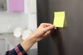 Woman putting blank sticky note on refrigerator door Royalty Free Stock Photo