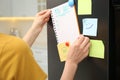 Woman putting blank to do list on refrigerator door in kitchen, closeup Royalty Free Stock Photo