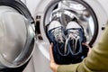 Woman putting blue sneakers in mesh laundry bag into washing machine, close up. Royalty Free Stock Photo