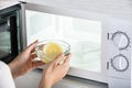 Woman Putting Bowl Of Slice Lemon In Microwave Oven