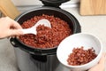 Woman putting brown rice into bowl from multi cooker in kitchen Royalty Free Stock Photo