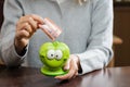 Woman putting business card in a funny green moneybox. Concept o