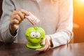 Woman putting business card in a funny green moneybox in rays of