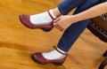 Woman putting on causal shoes while sitting on footstool at home