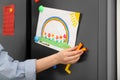 Woman putting child`s drawing on refrigerator door Royalty Free Stock Photo
