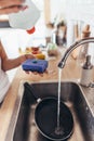 Woman putting cleanser to a sponge to wash pan in the kitchen-sink. Hand washing dishes. Close-up.