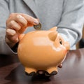 Woman putting coins in a funny piggy bank. Concept of future, bu