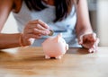 Woman putting coins to piggi bank