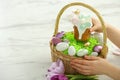 Woman putting delicious Easter cake with meringues into wicker basket at white marble table, closeup. Space for text Royalty Free Stock Photo