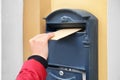 Woman putting envelope into mailbox on wall of building outdoors Royalty Free Stock Photo