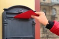 Woman putting envelope into mailbox on wall of building outdoors Royalty Free Stock Photo