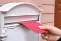 Woman putting envelope into mailbox on wall of building outdoors Royalty Free Stock Photo