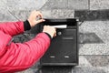 Woman putting envelope into mailbox on wall of building outdoors Royalty Free Stock Photo