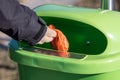 Woman putting a excrement bag from a dog into a waste bin contai