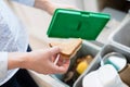 Close Of Woman Putting Food Waste Into Recycling Bin In Kitchen