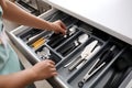 Woman putting fork into kitchen drawer