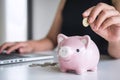 Woman putting golden coin in pink piggy bank for step up growing business to profit and saving with piggy bank, Saving money for Royalty Free Stock Photo