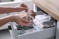 Woman putting heart shaped scented wax sachet into dresser drawer with folded clothes at home, closeup Royalty Free Stock Photo