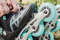 Woman putting on inline roller skates wheels in skatepark