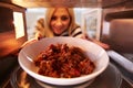 Woman Putting Leftover Chili Into Microwave Oven To Cook