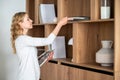 Woman putting magazines and journals on wooden shelf of cabinet Royalty Free Stock Photo