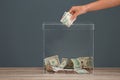 Woman putting money into donation box on table against grey background Royalty Free Stock Photo