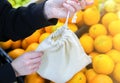 Woman is putting oranges in reusable shopping bag. Zero waste. Ecologically and environmentally friendly packets. Canvas and linen Royalty Free Stock Photo