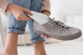 Woman putting orthopedic insole into shoe at home