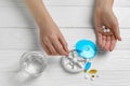 Woman putting pill into plastic box at white wooden table, top view Royalty Free Stock Photo