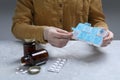 Woman putting pill into weekly organizer at grey marble table, closeup