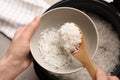 Woman putting rice into bowl from cooker in kitchen Royalty Free Stock Photo