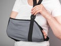 Woman putting on sling to support injured arm. Elbow, shoulder, forearm, wrist pain caused by trauma, injury, chronical Royalty Free Stock Photo