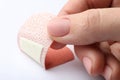 Woman putting sticking plaster on background, closeup. First aid item