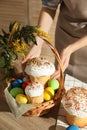 Woman putting traditional Easter cake in basket at table, closeup Royalty Free Stock Photo