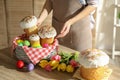 Woman putting traditional Easter cakes in basket indoors, closeup Royalty Free Stock Photo