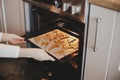 Woman putting tray with christmas cookies in oven close up in modern kitchen. Baking gingerbread cookies. Family holiday Royalty Free Stock Photo