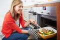 Woman Putting Tray Of Roast Vegetables Into Oven Royalty Free Stock Photo