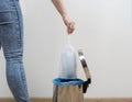 Woman is putting used disposal nonwoven safety mask packed in plastic bag into metal trash bin Royalty Free Stock Photo